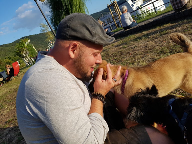 Deutschland Vanlife, Alex mit Hündin Muk auf der Wiese am Rhein