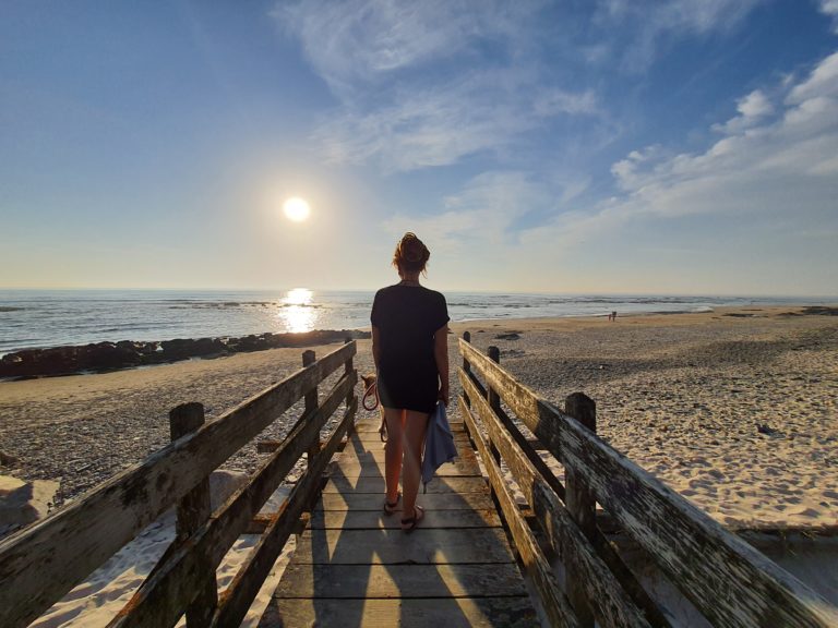 Portugal Vanlife Highlight, Kathy auf einem Holzsteg am Strand in Portugal bei Sonnenuntergang