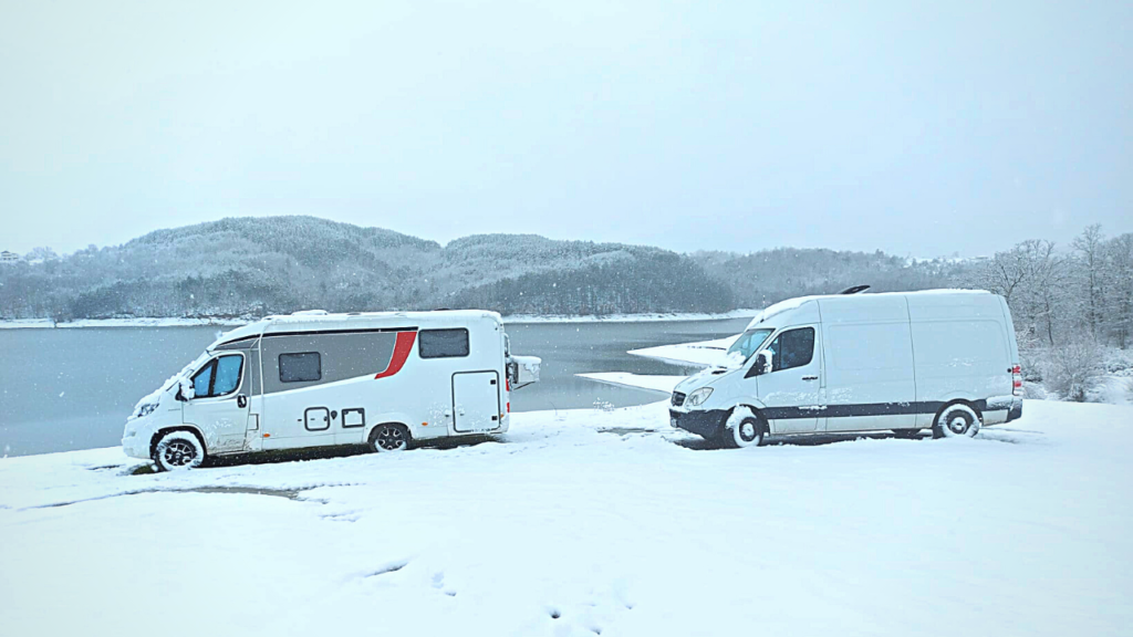 Zwei Campervans in Bulgarien im Schnee am See