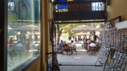 Kathy in Novi Sad bei Tag in der Fussgaengerzone Blick aus dem Souvenirladen auf ein Restaurant