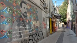 Kathy in Novi Sad bei Tag in der Fussgaengerzone in der Altstadt Graffiti an Hauswand